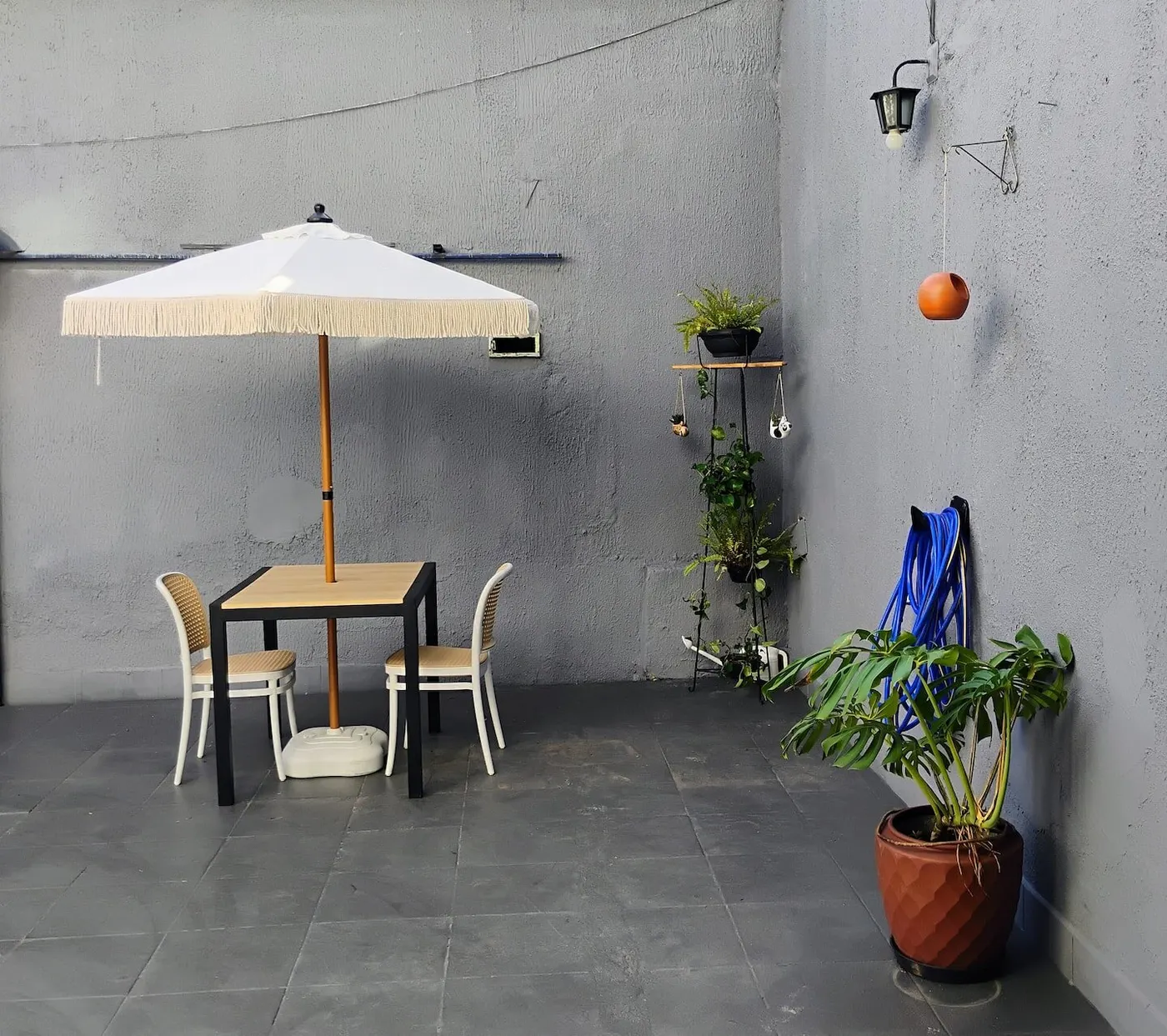 Varanda com guarda-sol, mesa, cadeiras e plantas